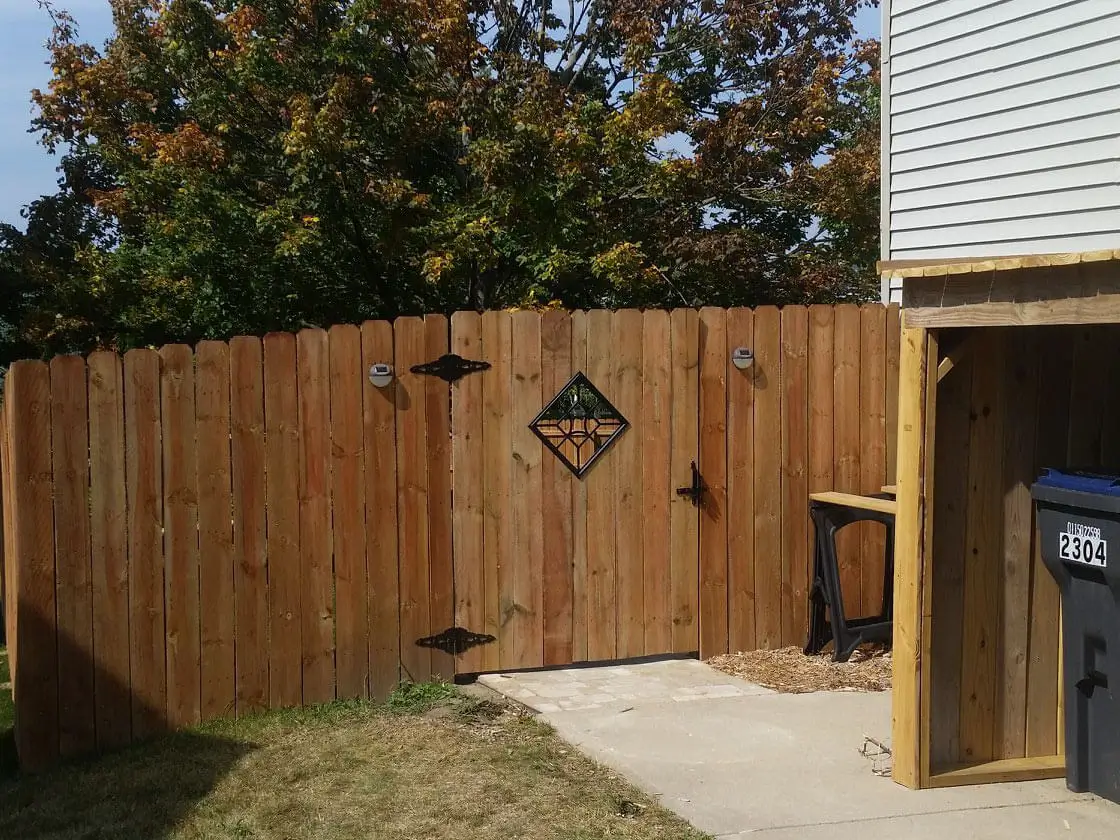 Full privacy wood fence with custom gate design installed around a residential property in Southern Wisconsin